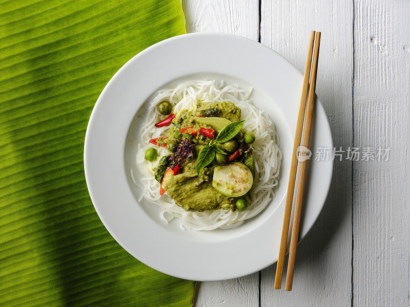 著名的国际知名的泰国绿椰子咖喱'Gaeng Keow Wan Gai'，鸡肉在新鲜的泰国米粉上，鸡肉在新鲜的泰国米粉上，在一个菜，连同传统的筷子。